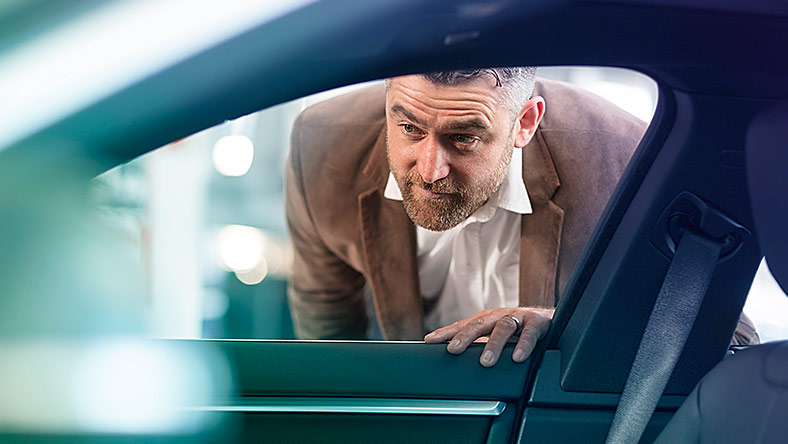 Man looking through car window to admire its interior