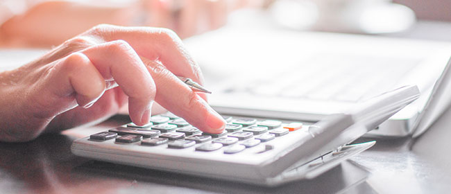 A man typing on a calculator - tax tips for students