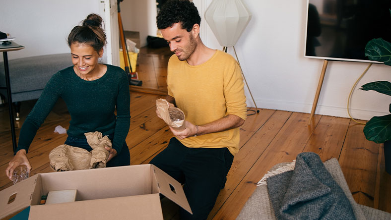 Couple sitting on floor unpacking in their new home