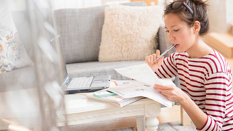 Woman sitting at coffee table calculating home loan expenses