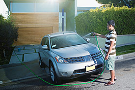 Man cleaning car with hose in his driveway