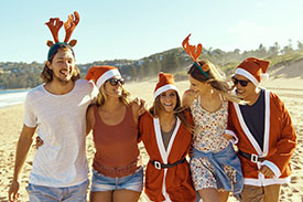 Tips for stress free Christmas travel - image of friends wearing Santa hats on the beach