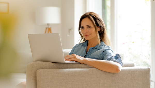 A woman works on her laptop while relaxing on her lounge.
