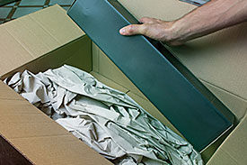 A male's hand taking an item out of a shipping box that he bought online.
