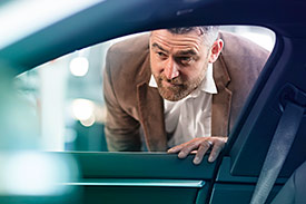 Man looking through car window to admire its interior