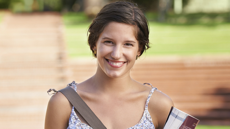 Smiling female university student walking to class