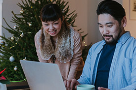 A young couple chat as they shop on their laptop