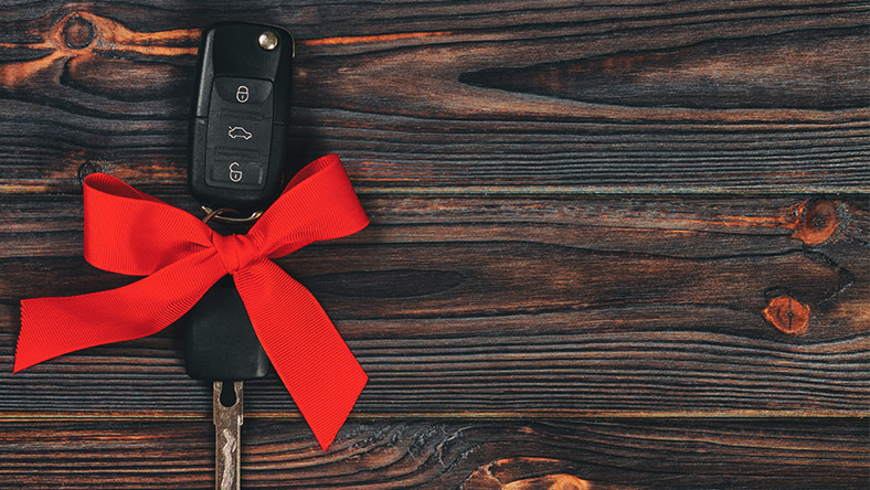 A set of keys sits upon a bench wrapped in a red ribbon.