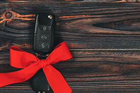 A set of keys sits upon a bench wrapped in a red ribbon.