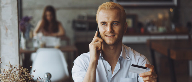 A young man on the phone with a credit card.