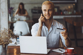 A young man on the phone with a credit card.