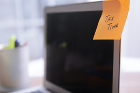 A computer monitor with an orange post-it note stuck on the screen, reading 