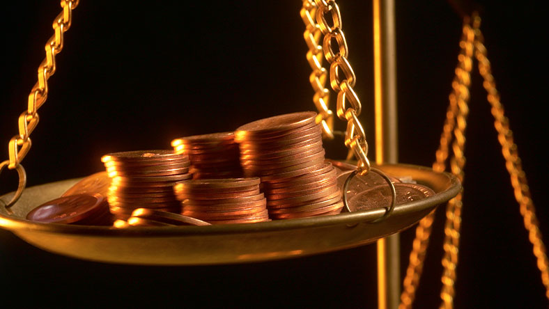 Stacks of gold coins sitting on gold scale 