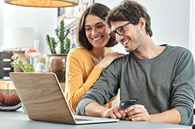 Your credit report - image of smiling couple sitting together in front of a laptop in a stylish apartment