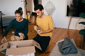 Couple sitting on floor unpacking in their new home