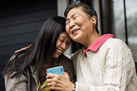 A mother and her daughter embrace sitting on their front steps.