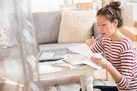 Woman sitting at coffee table calculating home loan expenses