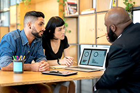 Three people looking at a laptop.