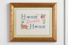 An embroidery reading Home Sweet Home sits framed upon the wall of a new home.