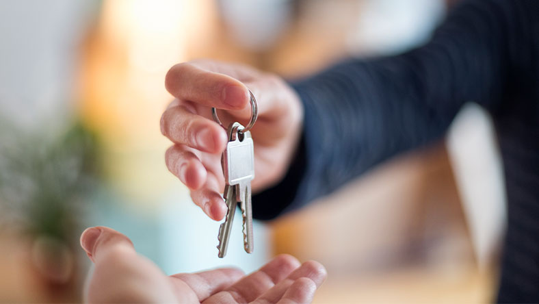 Close up of hand passing keys to new home owner