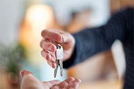 Close up of hand passing keys to new home owner