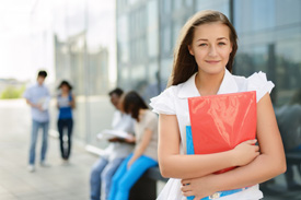 A young woman holding a folder and looking at the camera.