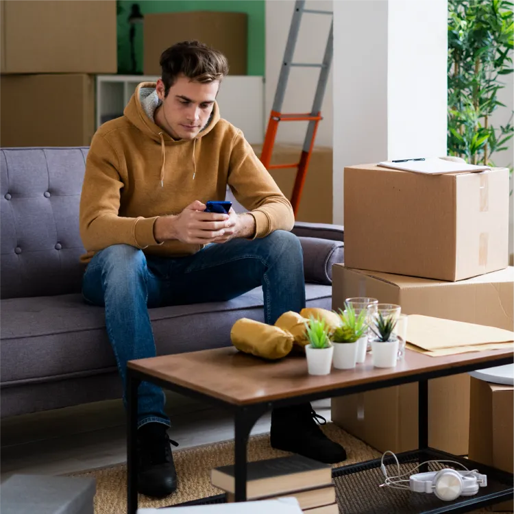 A young woman carries a cardboard box in her new living room.