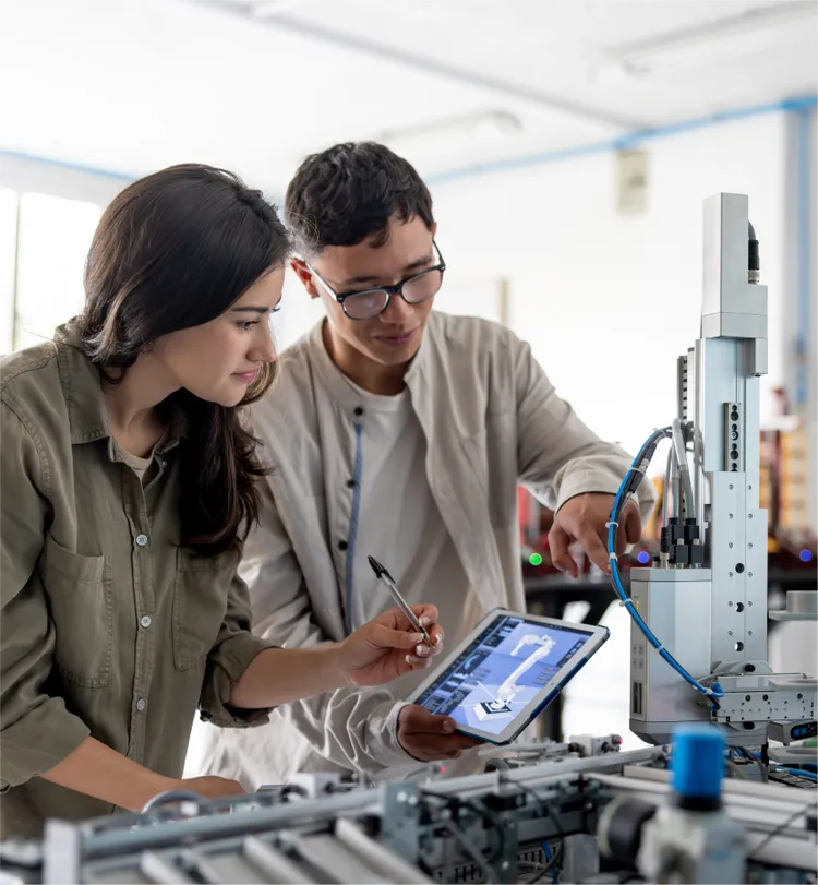 Two engineers collaborate in a modern industrial setting, focusing on an automated machine.