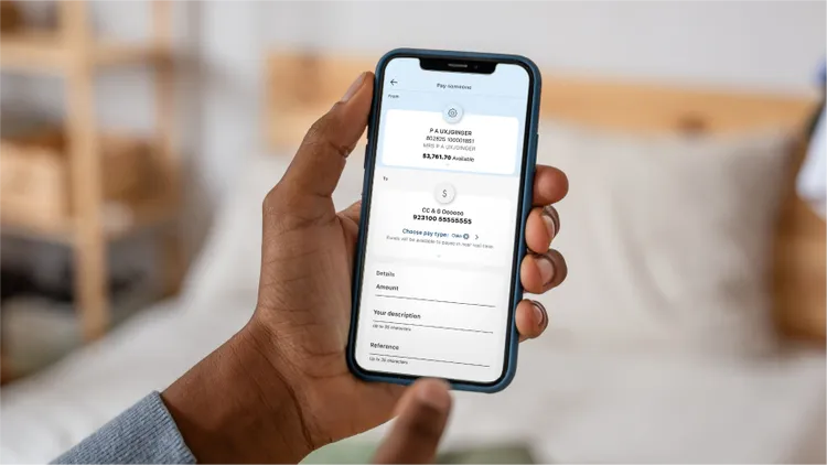 A person holds a smartphone displaying an online payment or banking interface.